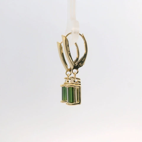 Earrings with green stones hanging from yellow gold hoop, side view