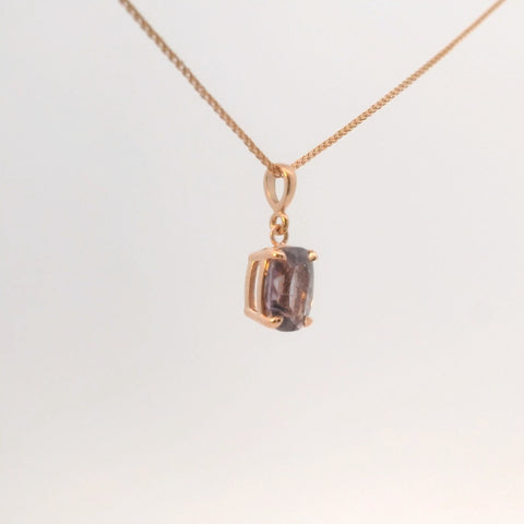 close-up of rose gold pendant with purple gemstone