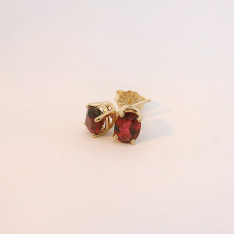 Gold earrings with red stones, angled view