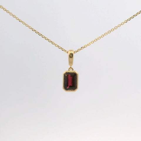 gold pendant with an emerald-cut red stone, front view