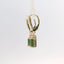 Earrings with green stones hanging from yellow gold hoop, side view