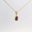 gold pendant with an emerald-cut red stone, side view