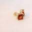 Gold tone earrings with red gemstones, angled view.